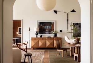 A modern minimalist living room featuring wooden furniture, a round wooden table, and a wooden credenza.