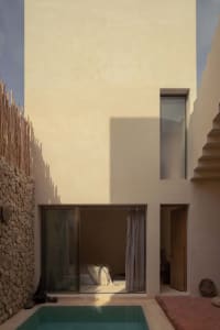 Modern minimalist house with concrete exterior and a small poolside area.