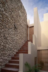 Modern building exterior featuring a stone wall and stairs.