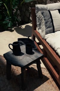 Outdoor wooden furniture with black cups and cushions.