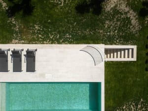 Modern luxury pool area with concrete deck and grassy landscape.
