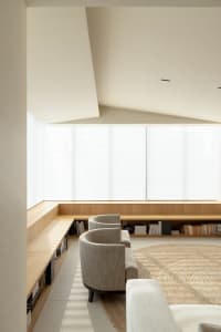 A minimalist living room featuring modern furniture, wood accents, and a circular jute rug, with a large window providing nat