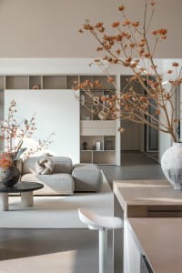Modern industrial living room with a minimalist design, featuring a sleek white couch, wooden furniture, and a vase of flower
