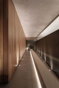 A modern, minimalist corridor with wooden walls and recessed lighting.