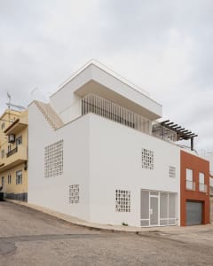 A modern residential building with concrete and glass features a rooftop staircase and a private balcony.