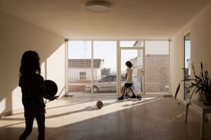 Children playing with a basketball and a scooter in an indoor space with ceramic flooring.