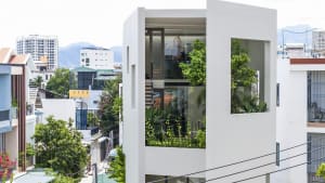 A modern residence featuring glass, concrete, and greenery elements.