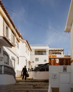 A residential street with concrete stairs, brick walls, and white-painted buildings in an urban setting.