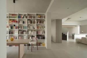 A minimalist library with light wood shelves and a wooden dining table with bananas
