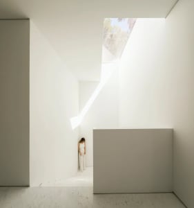 A minimalist interior space with a marble floor and concrete walls.