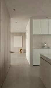 Modern minimalist kitchen with concrete flooring, white cabinets, and a minimalist light fixture.
