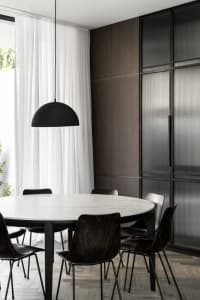 Modern minimalist dining room with marble table and dark wooden chairs