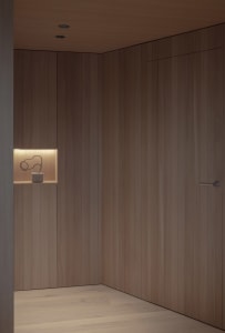 A minimalist closet with wooden panels and a small shelf with a sculptural object.
