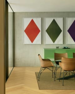A modern living room features a concrete wall, wooden furniture, and glass windows.