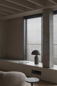 A modern minimalist living room with concrete walls, wooden floor, and white furniture.