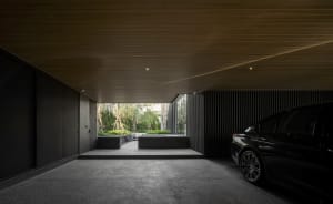 Modern carport with dark metal walls and a black car parked inside.