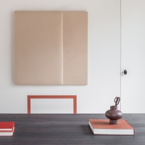 A modern minimalist interior with a desk, books, and decorative vase on a table.
