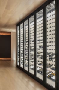 A modern wine cellar with glass doors filled with numerous bottles of wine.