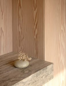 A ceramic vase with small white flowers on a wooden shelf.