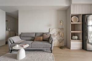 A minimalist living room with a gray couch adorned with cushions, a white coffee table, and a modern design aesthetic.