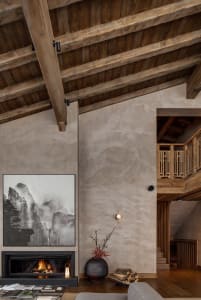 Minimalist living room with concrete fireplace and wooden beams on the ceiling.
