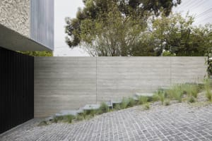 Modern concrete landscape design featuring greenery and a cobblestone pathway.
