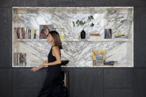 A modern marble bookshelf with black wood accents featuring various books and decorative items.
