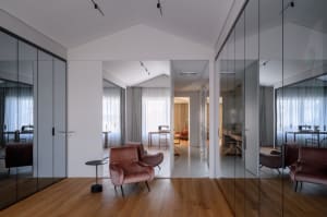Modern living room with wooden floors, glass walls, and fabric furniture.