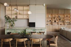 A modern residential kitchen with a marble countertop and wooden furniture.