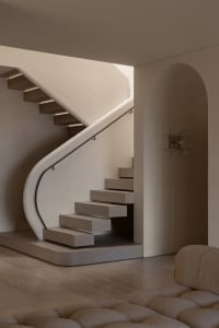 A minimalist staircase with wooden steps and a concrete wall, featuring a modern railing and a well-lit space.