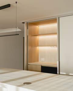 Modern minimalist closet featuring wood shelves with hidden lighting and a sleek, clean design.