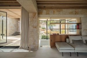 Modern living room with concrete walls and floor, featuring a comfortable sofa and bookshelf.