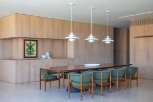 Modern dining room with wooden interiors and green upholstered chairs.