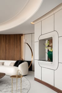 A modern minimalist living room with white furniture, wooden accents, and floral decor.