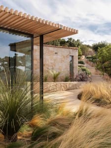 A modern stone home with a glass extension and a pergola.