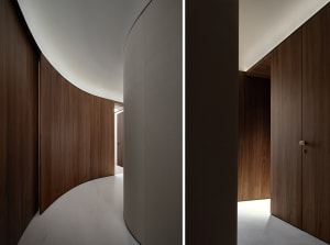 Modern interior corridor with curved wooden walls and white flooring.