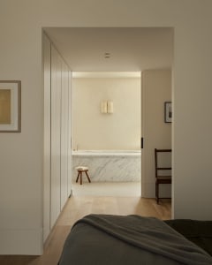 Modern minimalist bedroom with a marble bathtub in the background.