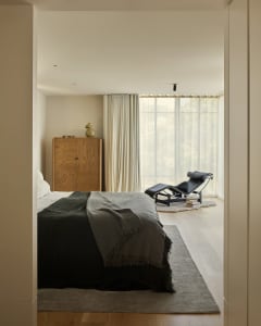 Minimalist bedroom featuring wood furniture and fabric accents.