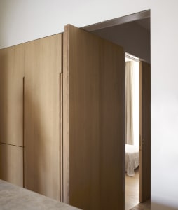 a minimalist residential interior with wooden details, featuring a bedroom with curtains opened.