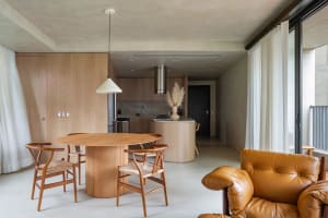 A modern, minimalist residential kitchen with a round dining table and wooden furniture.