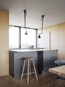 A modern minimalist kitchen with concrete countertops and wooden stools