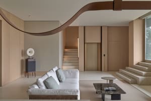 Modern, minimalist living room with neutral-toned walls, grey sofa, marble coffee table, and wooden cabinets.