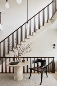 Modern staircase entryway with marble furniture and plant.