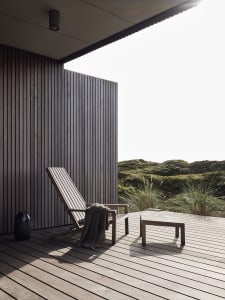 A minimalist outdoor lounge area featuring modern wooden furniture and a relaxing atmosphere.
