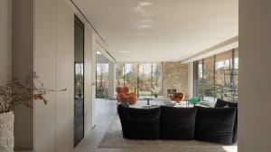 Modern living room with glass walls, stone fireplace, and wooden furniture.