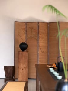 A serene tea house interior featuring a bamboo screen and traditional tea table.