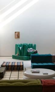 A modern interior design featuring a teal sofa with a concrete floor and high ceiling.