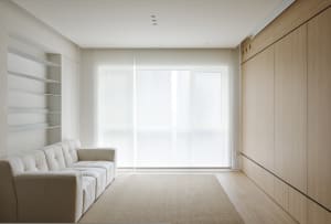 Minimalist living room with white furniture and wooden walls.