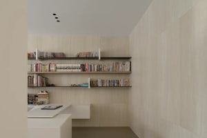 A well-organized and modern home office with floating shelves filled with books and a desk with a notebook and pen.