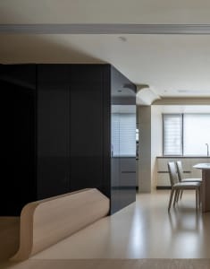 Modern kitchen with black glass cabinets, white marble countertops, and concrete flooring.